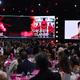 Two screens, one bearing promotional images for Squid Game, another of actor Lee Jung-Jae accepts an award.
